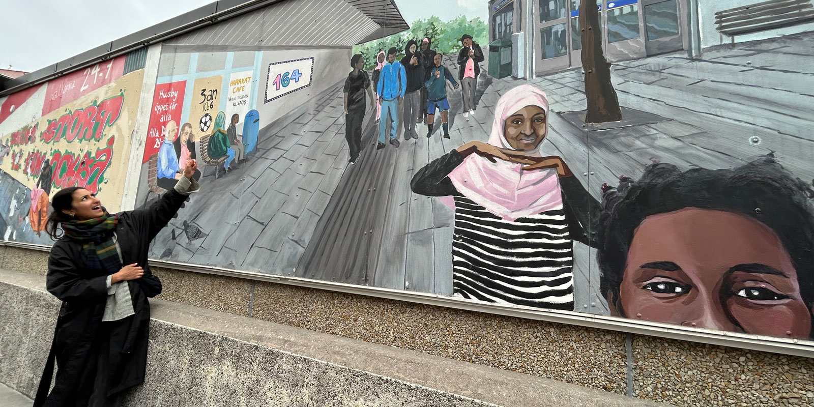 En kvinna pekar på en muralmålning.